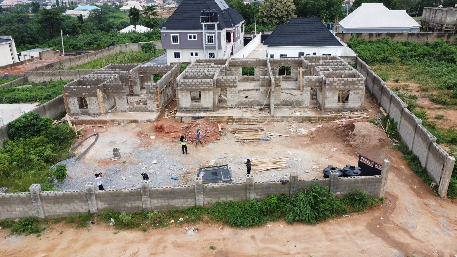 Aerial view of the Eden site at week 10: ground-floor walls at full height on all three homes with door and window openings formed