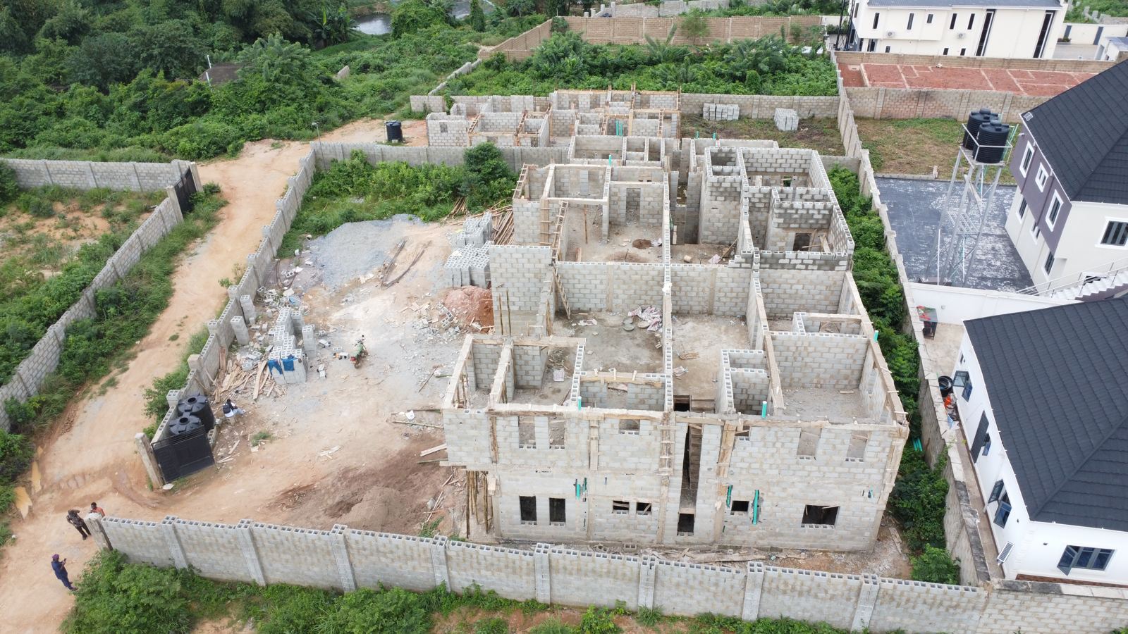 Aerial view of the Eden site at weeks 15 and 16: first-floor walls rising on the two-storey block above the cured slab, with scaffolding along the front