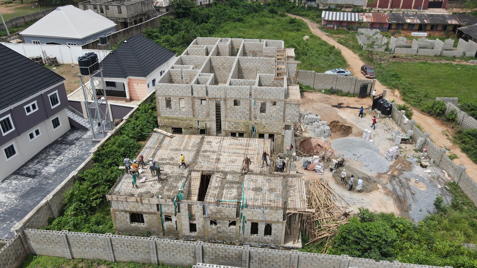 Workers casting a first-floor concrete slab at the Eden site in week 19, with the two-storey block behind them